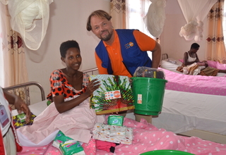 A refugee new mother receives a dignity kit after a few hours of birth from Mr. Mark Bryan Schreiner, UNFPA Rep.